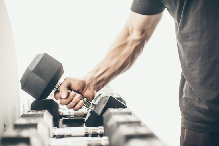 Man's arm lifting dumbell from the rack.